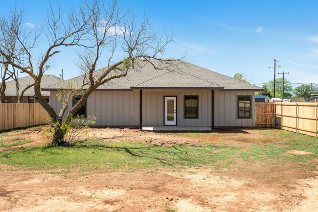 Rear view of house with board and batten siding, roof with shingles, and a fenced backyard | Image 28