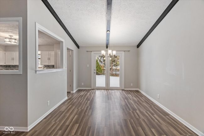 unfurnished dining area featuring a textured ceiling, a chandelier, dark wood-style flooring, and vaulted ceiling | Image 7