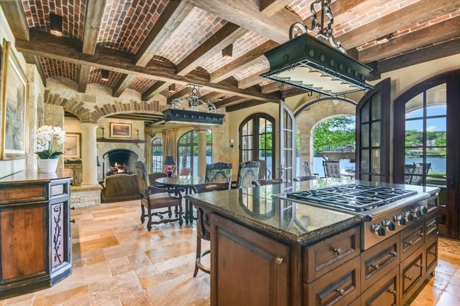 Kitchen featuring stone tile flooring, stainless steel gas stovetop, beam ceiling, and brick ceiling | Image 15