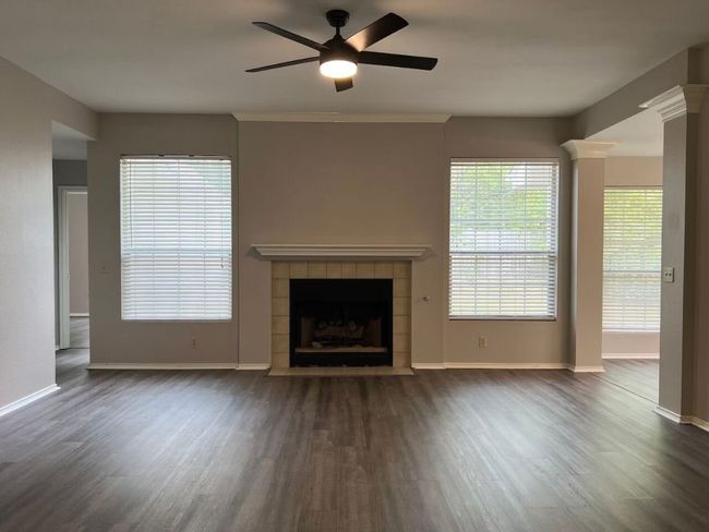 Unfurnished living room with dark wood-style flooring, a ceiling fan, and a fireplace | Image 6