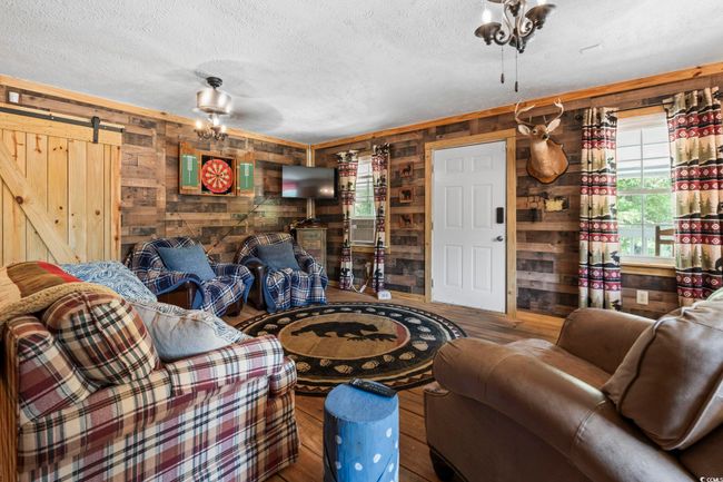 Living area featuring wooden walls, hardwood / wood-style floors, a barn door, and a textured ceiling | Image 10