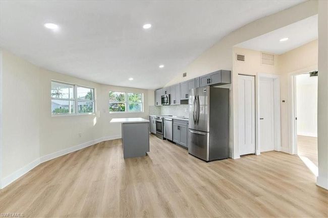 Kitchen featuring stainless steel appliances, gray cabinetry, light countertops, light wood-type flooring, and a kitchen island - VIRTUALLY EDIT PHOTO | Image 10