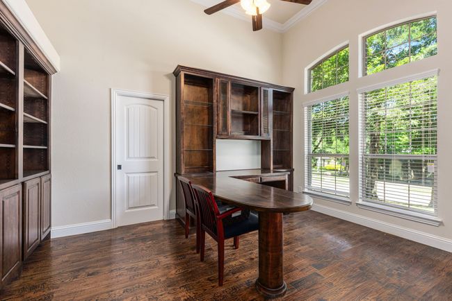 Home office with a ceiling fan, crown molding, a towering ceiling, baseboards, and dark wood-style floors | Image 12