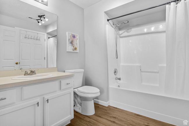 Full bath with wood finished floors, toilet, shower / tub combo with curtain, vanity, and baseboards | Image 10
