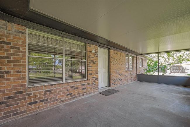 Leading out of living area, covered back patio offers plenty of space for outdoor activities and relaxation, with a view of the backyard through screened panels. Enjoy the beauty of your backyard rain or shine! | Image 24