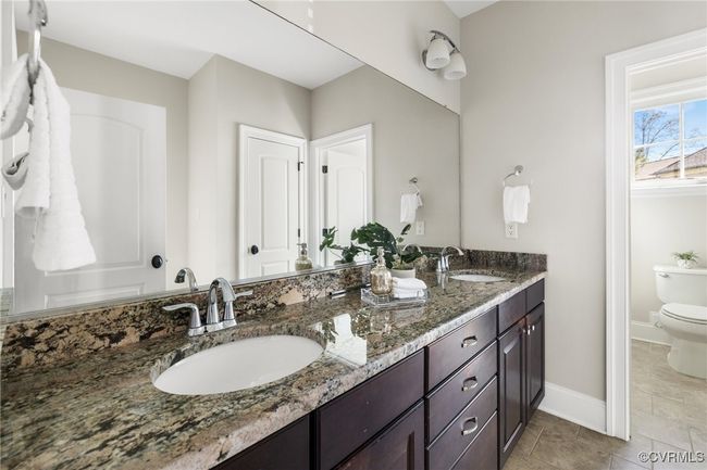 2nd floor hall bathroom; tile floors, raised granite double vanity sinks, tile surround/ceramic tub shower, toilet. | Image 22