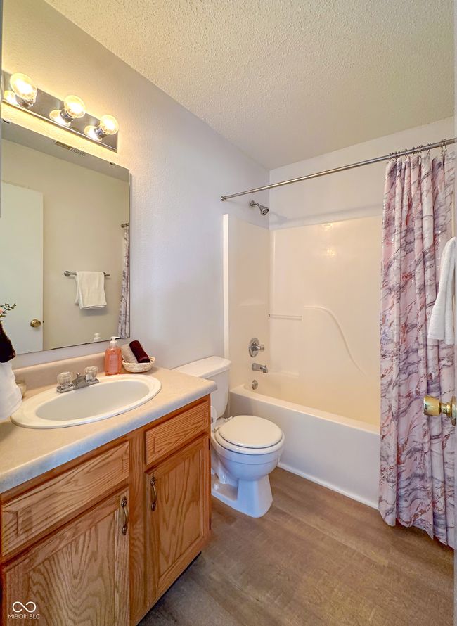 bathroom with vanity, shower / bath combo, a textured ceiling, toilet, and wood finished floors | Image 11