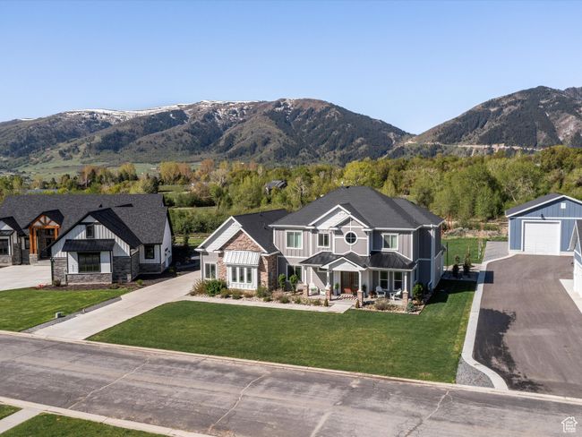 View of front facade featuring a mountain view, a detached garage, board and batten siding, a front lawn, and asphalt driveway | Image 47