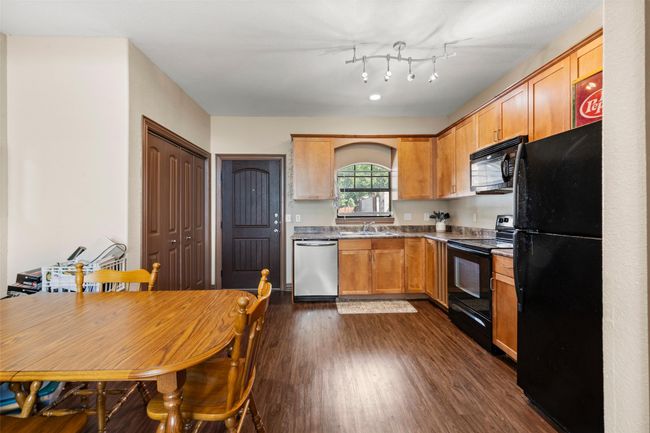 Kitchen with black appliances, dark wood finished floors, and dark countertops | Image 7