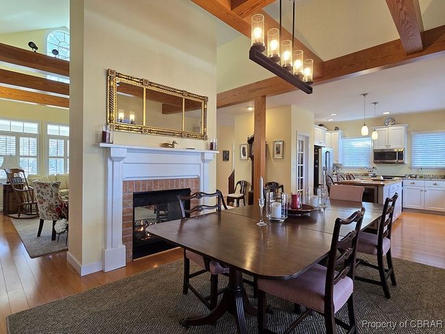 Dining space with beamed ceiling, a towering ceiling, wood finished floors, and a fireplace | Image 14