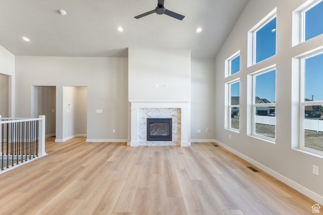 Unfurnished living room with ceiling fan, light wood-style flooring, a fireplace, and recessed lighting | Image 14