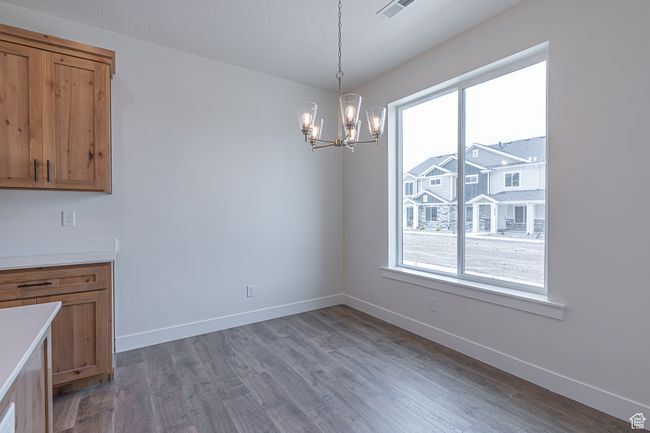 Unfurnished dining area with healthy amount of natural light, a chandelier, and wood finished floors | Image 6