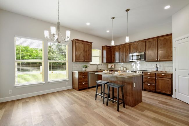 Kitchen with appliances with stainless steel finishes, a center island, decorative backsplash, light wood-style flooring, and recessed lighting | Image 7
