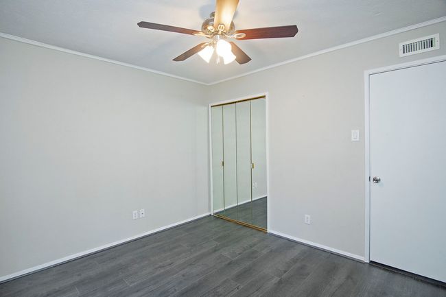 Unfurnished bedroom with crown molding, dark hardwood / wood-style floors, ceiling fan, and a closet | Image 25