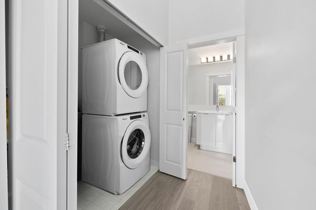 Washroom featuring light wood-type flooring, stacked washer and dryer, and laundry area | Image 22