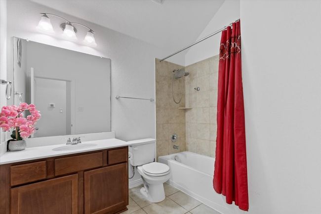 Bathroom with shower / bath combo, vanity, toilet, lofted ceiling, and tile patterned flooring | Image 21