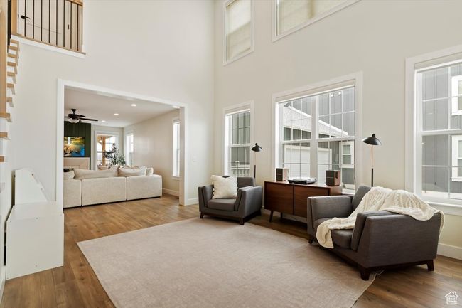 Living area with baseboards, wood finished floors, and a high ceiling | Image 5