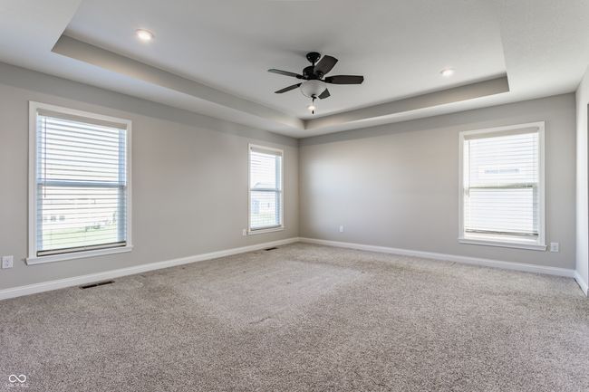 carpeted spare room featuring a tray ceiling, visible vents, baseboards, and ceiling fan | Image 26