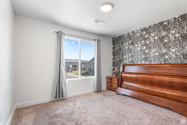 Bedroom featuring a textured ceiling, carpet, baseboards, and an accent wall | Image 25
