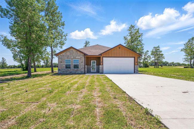 View of front of house with a front lawn, driveway, stone siding, board and batten siding, and a garage | Image 27