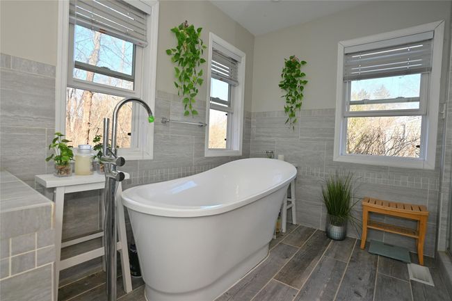 En-suite with a bathtub, tile walls, and hardwood / wood-style flooring | Image 17