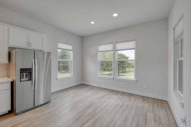 Kitchen featuring stainless steel fridge with ice dispenser, light wood-style flooring, light countertops, white cabinetry, and recessed lighting | Image 13