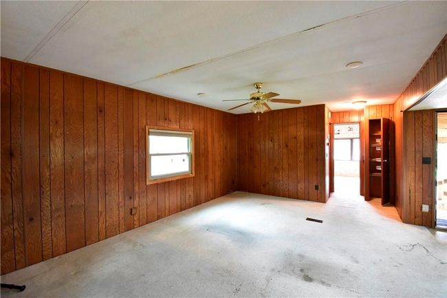 Empty room featuring ceiling fan and wood walls | Image 25