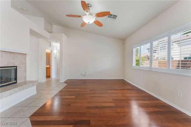 Unfurnished living room featuring a ceiling fan, lofted ceiling, a tile fireplace, light wood finished floors, and baseboards | Image 11