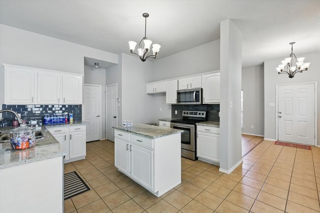Kitchen featuring appliances with stainless steel finishes, a chandelier, and light tile patterned floors | Image 12