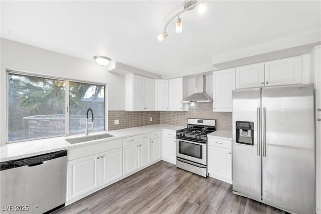 Kitchen featuring wall chimney exhaust hood, a sink, appliances with stainless steel finishes, and light countertops | Image 4