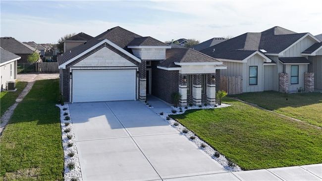 View of front facade with a garage, central AC, driveway, board and batten siding, and a front yard | Image 24