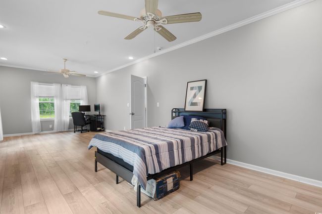 Bedroom with an office area, baseboards, recessed lighting, light wood-style flooring, and ornamental molding | Image 22