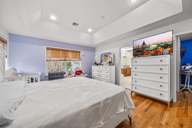 Bedroom with visible vents, a tray ceiling, recessed lighting, connected bathroom, and wood finished floors | Image 22