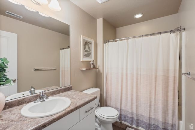 Bathroom featuring shower / bath combo, toilet, vanity, and visible vents | Image 21