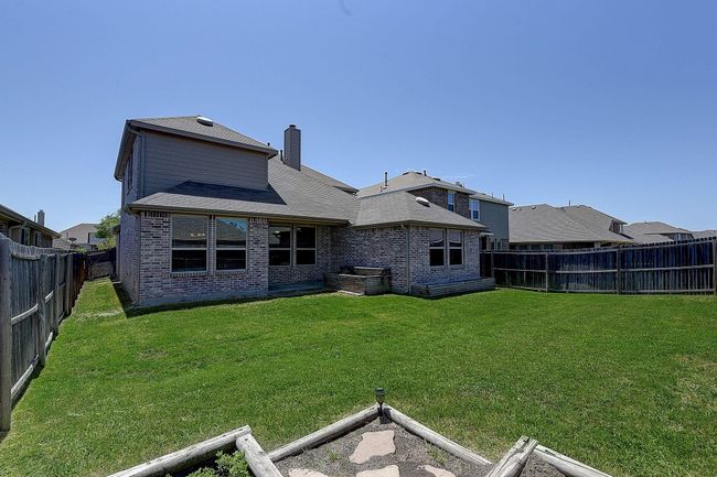 Back of house with brick siding, a chimney, and roof with shingles | Image 23
