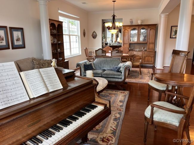 Living room with a chandelier, decorative columns, and dark wood-type flooring | Image 11