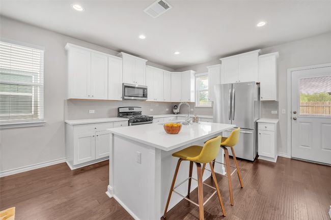 Kitchen featuring appliances with stainless steel finishes, dark wood-style flooring, backsplash, a sink, and light countertops | Image 6