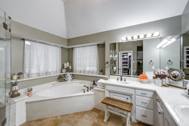 Bathroom featuring a sink, double vanity, a garden tub, a stall shower, and lofted ceiling | Image 24