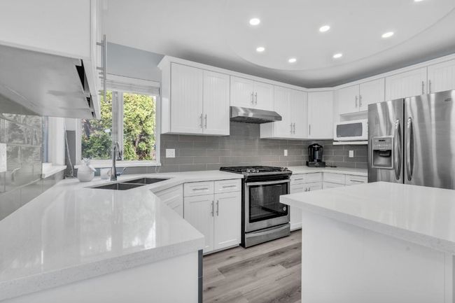 Kitchen with under cabinet range hood, decorative backsplash, stainless steel appliances, and a sink | Image 11