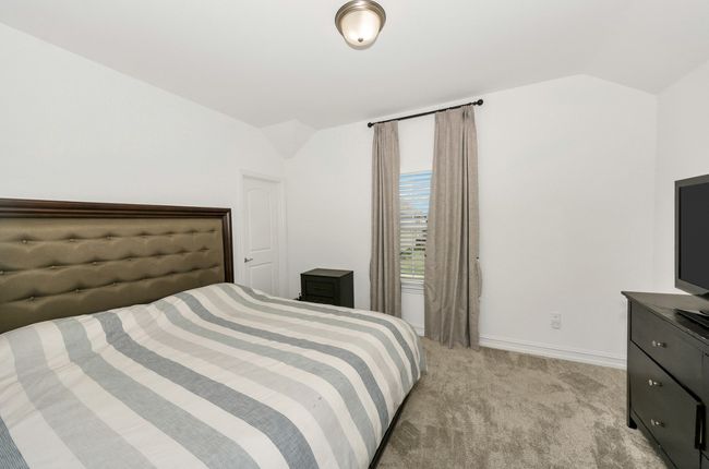 Bedroom featuring light colored carpet, vaulted ceiling, and baseboards | Image 22