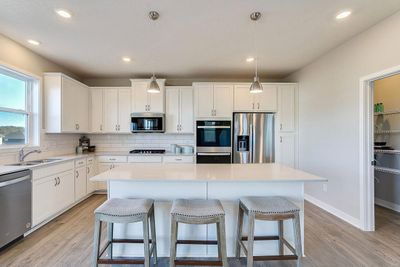 Actual photo of home. Oversized island, stainless appliances, gas cooktop, and vented microwave to outside. | Image 3