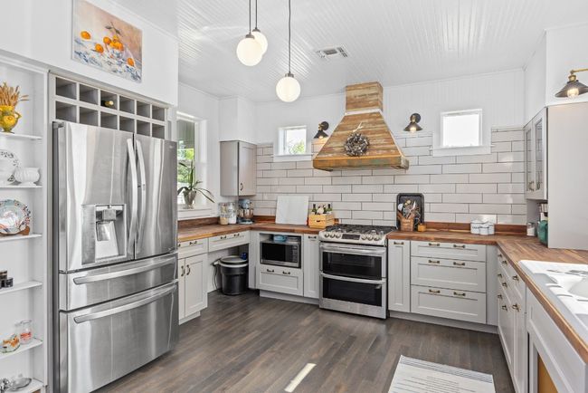 Kitchen with wood counters, stainless steel appliances, custom exhaust hood, and open shelves | Image 11
