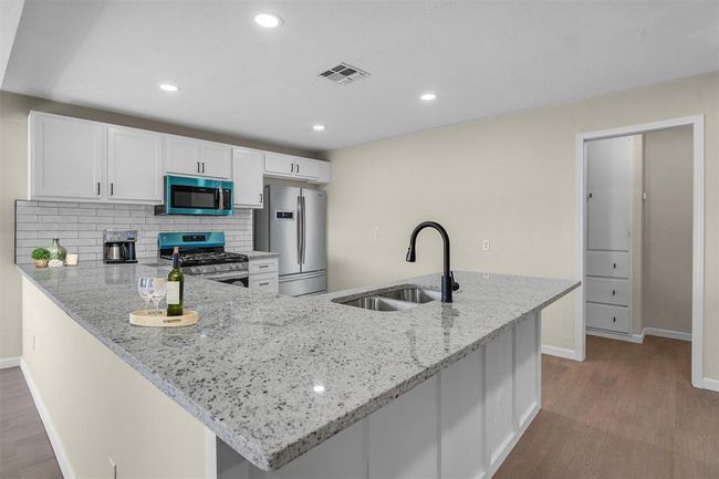 Kitchen with stainless steel appliances, sink, kitchen peninsula, backsplash, and light wood-type flooring | Image 21