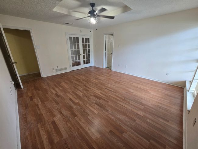 Empty room featuring wood finished floors, a ceiling fan, french doors, and a textured ceiling | Image 12