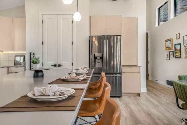 Interior space with cream cabinetry, light wood-type flooring, stainless steel fridge, and a high ceiling | Image 9