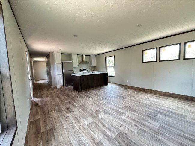 Kitchen featuring a textured ceiling, light countertops, open floor plan, light wood look-style flooring, and freestanding refrigerator | Image 22