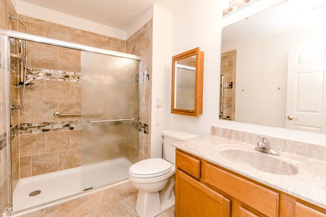 bathroom with vanity, toilet, and tiled shower | Image 16