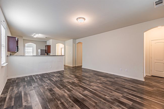 Unfurnished living room featuring dark wood-type flooring, plenty of natural light, and arched walkways | Image 15
