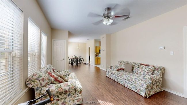 Living room with visible vents, ceiling fan, wood finished floors, and baseboards | Image 6