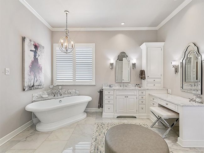Full bathroom featuring a freestanding bath, a chandelier, marble finish floors, vanity, and crown molding | Image 23